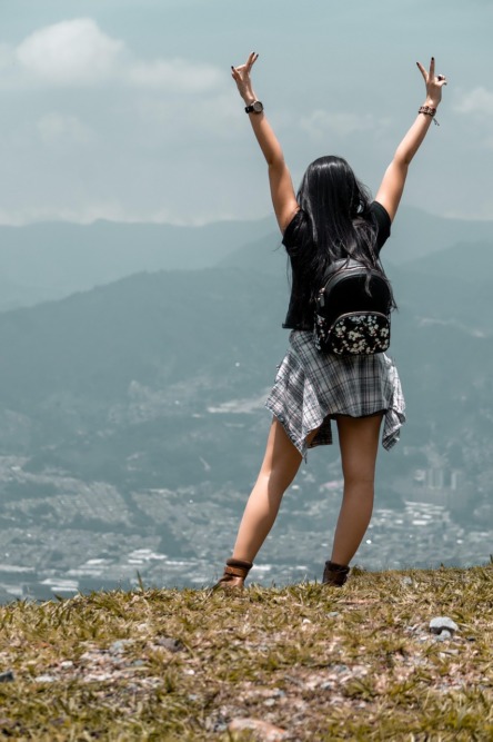 chica de espaldas observando un paisaje montañoso y posando para una fotografía
