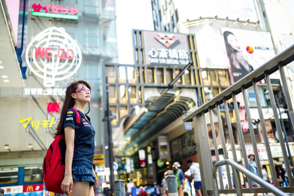 chica con una mochila y gafas en el bullicio de una ciudad china observando su alrededor