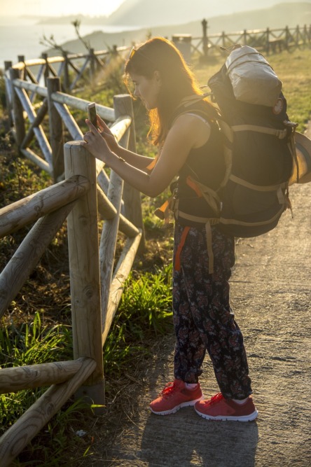 chica con mochila de viajero realizando una fotografía al paisaje